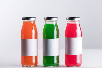 Plakat row of glass bottles with multicolored liquid and white blank labels isolated on grey