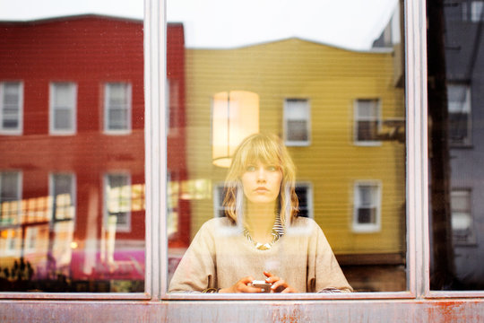 Blond young woman seen through glass window