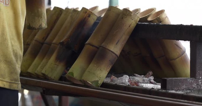 Glutinous rice roasted in bamboo joints on metal oven, street food in Thailand.