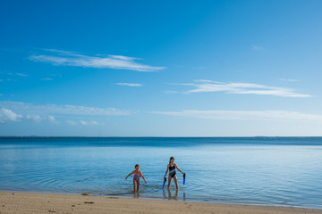 Fototapeta na wymiar two girls walking out of calm tropical water