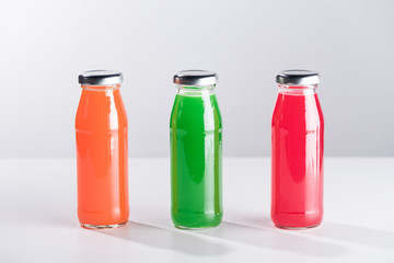 row of glass bottles with multicolored liquid isolated on grey