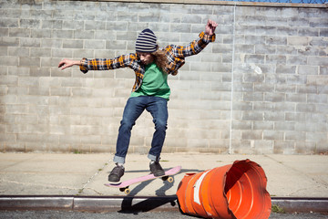Young man skateboarding against gray wall © Cavan for Adobe