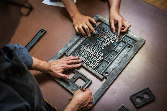 Craftsmen working with letterpress in workshop