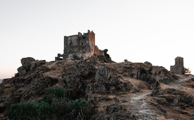 ruined castle at the top of the hill in a sunset