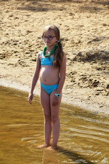little girl in swimwear on the shore of the lake