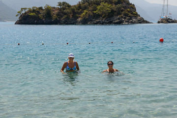 Women are posing in shallow water of Oludeniz beach, Turkey.