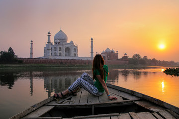 Woman watching sunset over Taj Mahal from a boat, Agra, India - obrazy, fototapety, plakaty