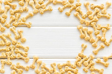 Dry dog food in shape of bone frame on white wooden background top view copyspace