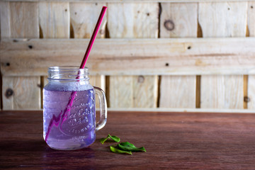 Un cóctel de bebida púrpura fresca en una taza de vidrio en mesa de madera rústica