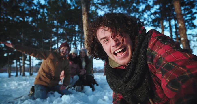 Man very charismatic with large smile and curly hair with his friends make a very excited video holding camera and make a funny faces very enthusiastic on the winter trip
