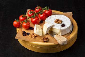 cheese board - camembert cheese with nuts, cranberries and cherry tomatoes