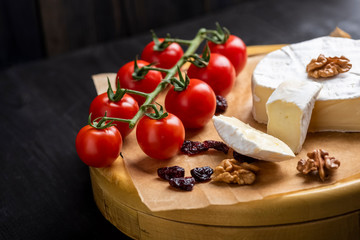 cheese board - camembert cheese with nuts, cranberries and cherry tomatoes