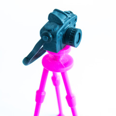 Toy black camera on a pink tripod