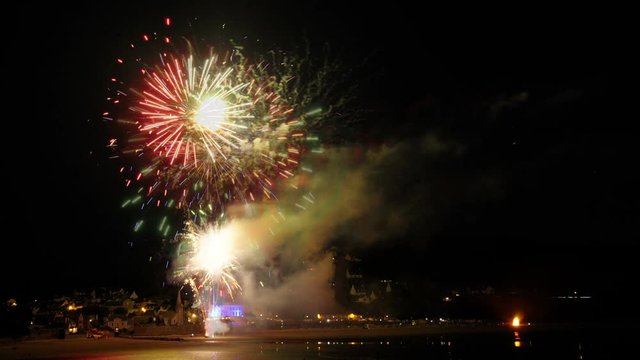 Timelapse with slow motion effect by superpositions of the pictures fading. Colorful show at night over a coastal village. 4K animated footage.
