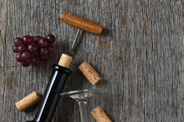 Wine still life with bottle corkscrew, grapes on a rustic wood table