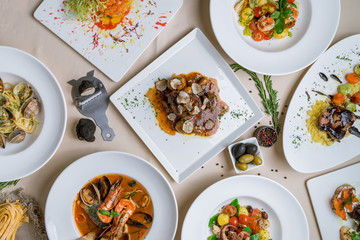 Assorted foodset of European food on table. Seafood casserole bowl, file minion with truffle, vongole, salad with octopus, salad with shrimps