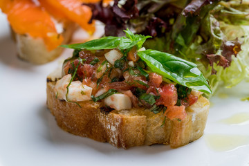 bruschetta with tomatoes and cheese on white plate closeup