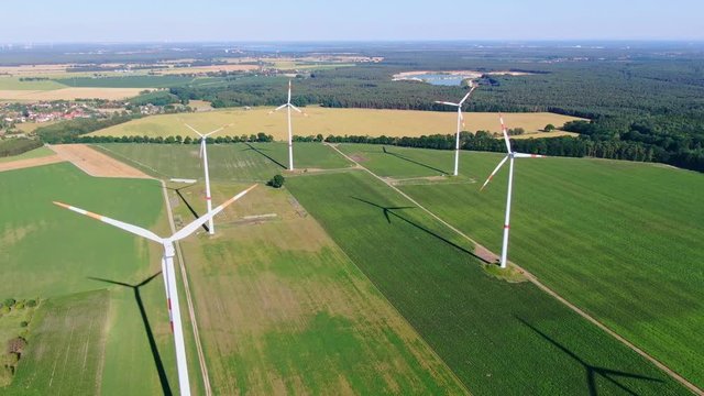 Aerial drone view of five wind power turbines, part of a wind farm, on a green field in eastern Germany near the city of Cottbus, Brandenburg. Wind turbines are part of the energy transition strategy.