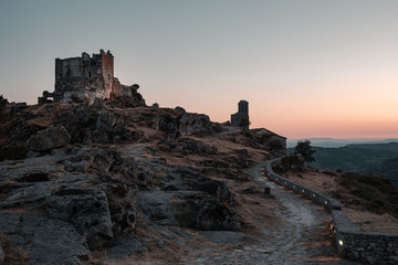 ruined castle at the top of the hill in a sunset