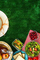 picnic in summer with products, sandwich, salad, fruits, drink and hat on green grass texture background top view mockup