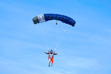 Skydiver with a dark blue parachute on the background a blue sky, close-up