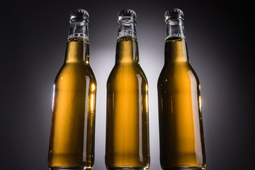 low angle view of glass bottles with beer on dark background with back light