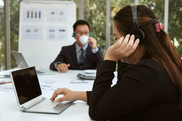 Senior secretary listen music while searching the data during meeting with managing director