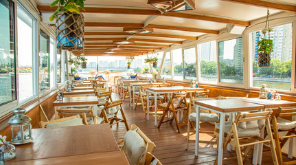 The interior of the urban river ship, with a panoramic view of the urban landscape. The concept of tourism, recreation, walking around the city, rest in the city. River transport.