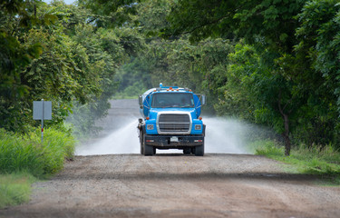 Obraz na płótnie Canvas Water Truck irrigating a dirt road to keep dust down
