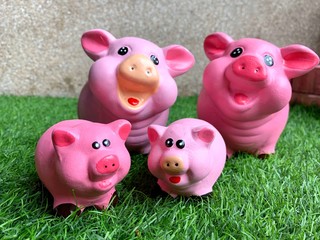The family of pink pig doll statues that smiling and happy faces are placed on a green lawn.