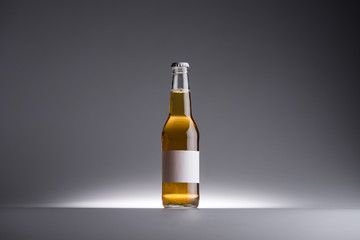 glass bottle with beer and blank label on dark grey background