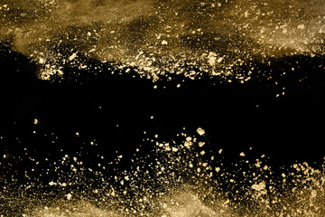 Golden powder explosion on black background. Freeze motion.