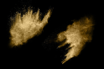 Golden powder explosion on black background. Freeze motion.