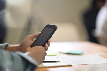 Man's hands holding mobile phone on table with copy space.