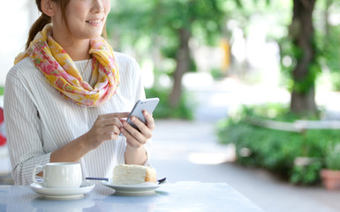カフェでスマートフォンを操作する女性
