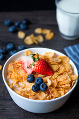 Breakfast cereal bowl with healthy blueberries and strawberries goes well with milk. Blue white stripes napkin