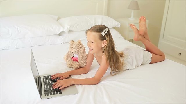 Cute little girl doing homework on laptop