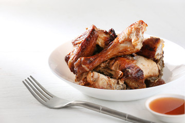 Grilled chicken in a white plate on a white wooden floor