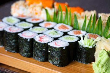 Asian food sushi rolls, wasabi and noodle on wooden plate close up.