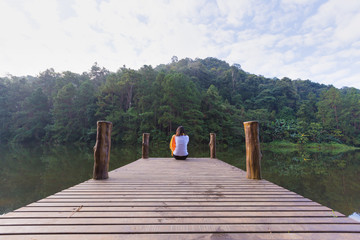 Woman sitting on a wooden bridge