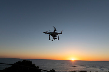 Fototapeta na wymiar Professional or Prosumer Drone flying over the sea at Sunrise