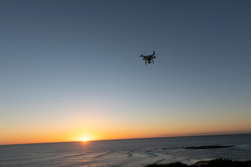 Fototapeta na wymiar Professional or Prosumer Drone flying over the sea at Sunrise