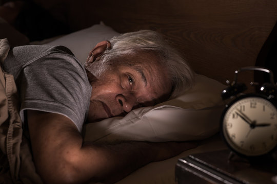 Depressed senior man lying in bed cannot sleep from insomnia