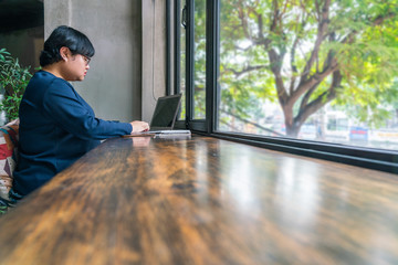 Asian female student using laptop at beautiful garden view coffeeshop