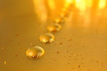 Golden drop row with gold glitter on golden blurred background.water drops . Drops pattern.Gold abstract background. Shining phone wallpaper