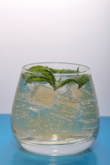 Refreshing drink with gas bubbles. Nalit in a transparent glass. It laid crushed ice. Decorated with mint leaves.