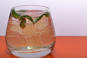 Refreshing drink with gas bubbles. Nalit in a transparent glass. It laid crushed ice. Decorated with mint leaves.
