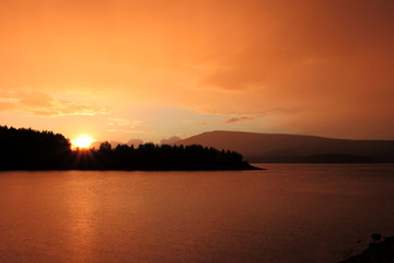 Fototapeta premium red and orange clouds at sunset over a mountain lake