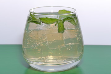 Refreshing drink with gas bubbles. Nalit in a transparent glass. It laid crushed ice. Decorated with mint leaves.