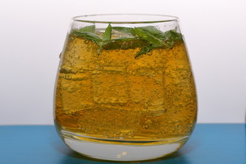 Refreshing drink with gas bubbles. Nalit in a transparent glass. It laid crushed ice. Decorated with mint leaves.